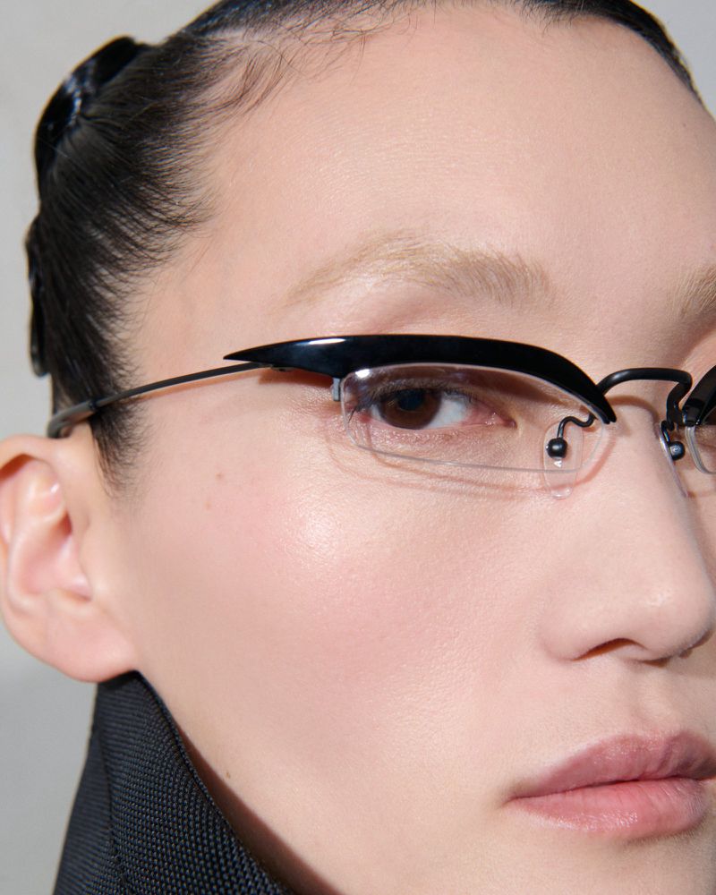 Close-up of an adult female with fair skin wearing unique black-rimmed glasses, showcasing beauty and fashion in a studio setting.
