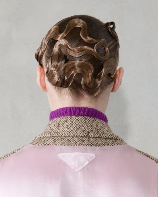 Close-up of a person with a vintage hairstyle, wearing a tweed jacket and purple top, showcasing fashion and beauty details.