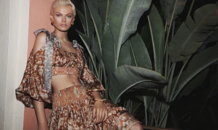 Model Cara Taylor in a floral two-piece outfit posing against tropical foliage for Zimmermann Summer Swim