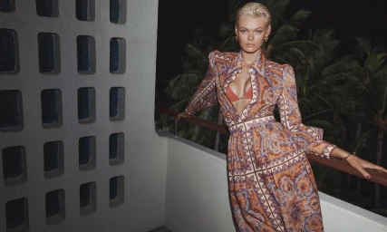 Model Cara Taylor wearing a patterned Zimmermann dress standing on a balcony at night for the Summer Swim campaign shot by Benny Horne.