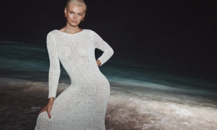 Model wearing a white knit dress posing on a dark beach at night for Zimmermann Summer Swim