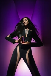 Model wearing a black cut-out suit holding a Mugler perfume bottle against a purple and pink gradient studio background.