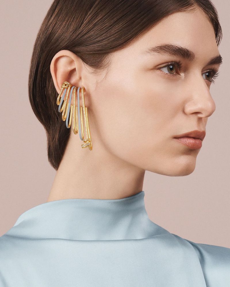 Elegant portrait of a woman showcasing a long, gold, statement ear cuff. The jewelry accentuates her face and complements her fashion style.