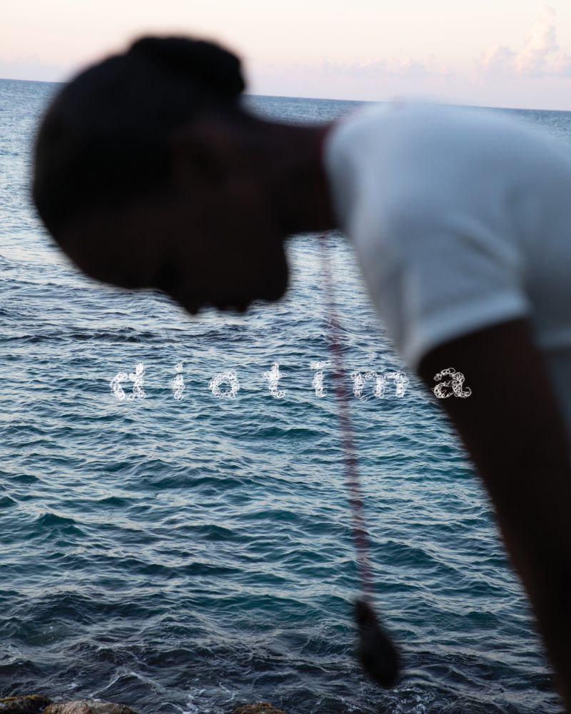 A blurry, artistic outdoor shot of a person in a white shirt standing by the ocean with stylized text overlay, evoking a dreamy, contemplative mood.