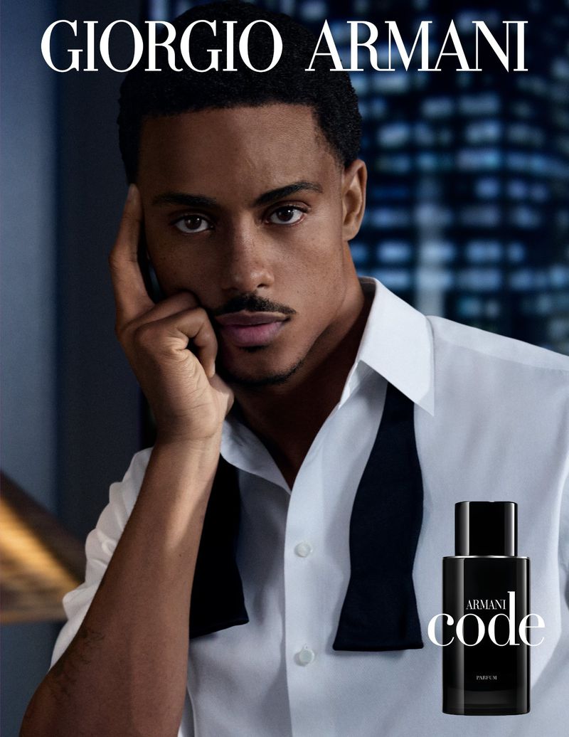 Man poses with Armani Code fragrance. Close-up of adult male in a white shirt and black tie with the Armani perfume bottle.