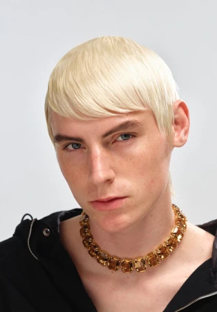 Platinum blonde model wearing an amber gemstone choker necklace and black hoodie against a plain studio background.