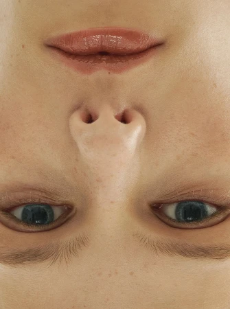 Extreme close-up, upside-down portrait of a woman with blue eyes, light freckles, and glossy pink lips filling the entire frame.