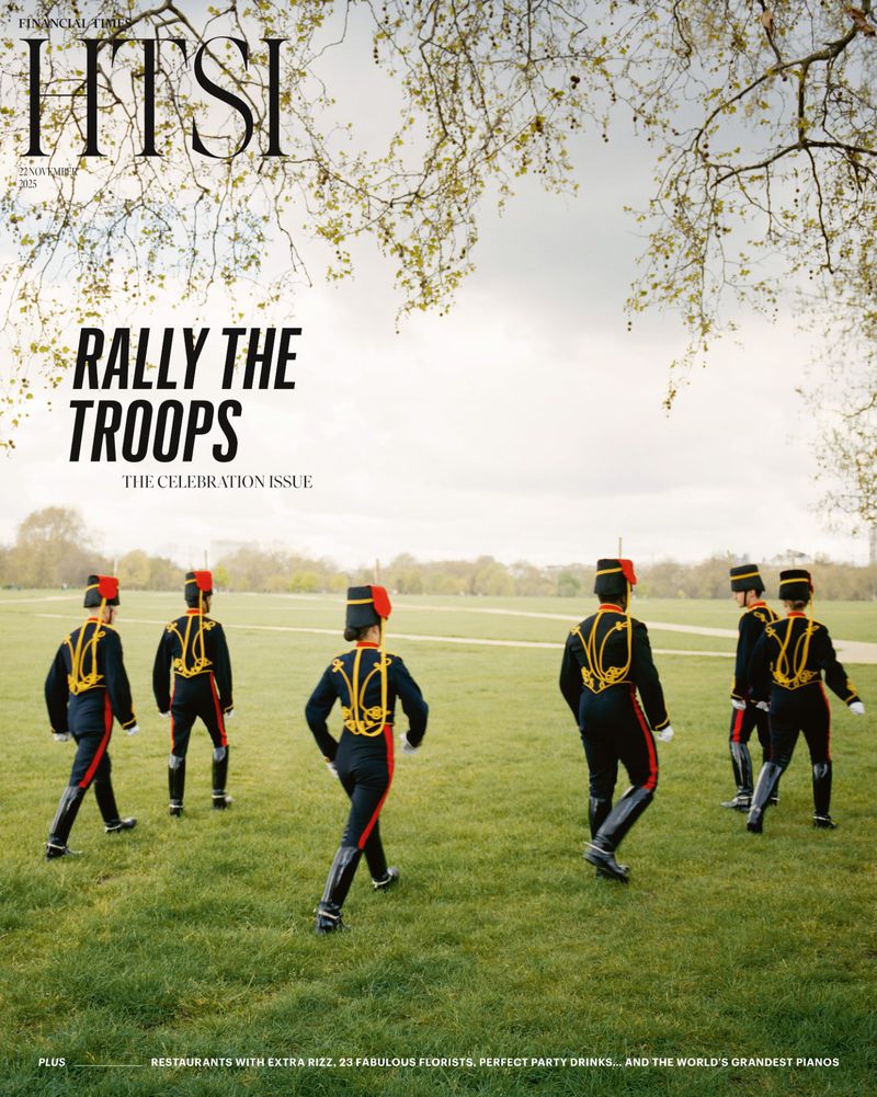 Magazine cover featuring six people in black and red marching band uniforms walking on green grass under a tree canopy.