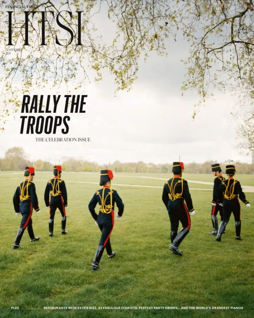 Magazine cover featuring six people in black and red marching band uniforms walking on green grass under a tree canopy.