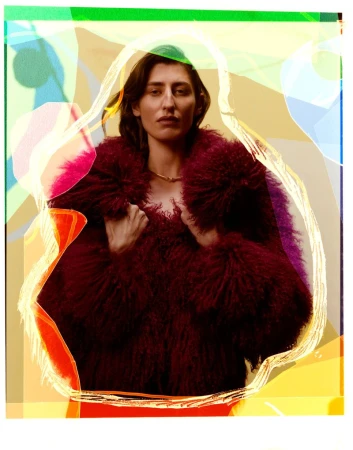 Portrait of an adult female in a fuzzy burgundy coat against an abstract background featuring geometric shapes and light pastel colors.