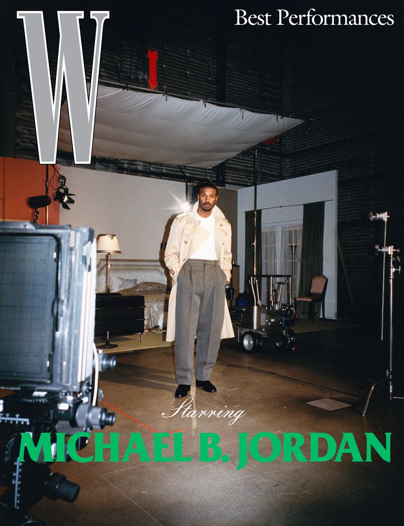 Magazine cover featuring Michael B. Jordan in a light trench coat and gray pants, posing in a film studio with cameras and lighting equipment.