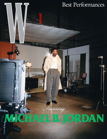 Magazine cover featuring Michael B. Jordan in a light trench coat and gray pants, posing in a film studio with cameras and lighting equipment.