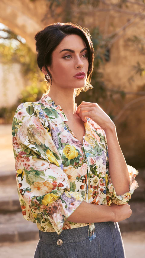 Woman wearing a floral print blouse and grey skirt outdoors in a sunlit historic setting, photographed by Steve Tognazzini.