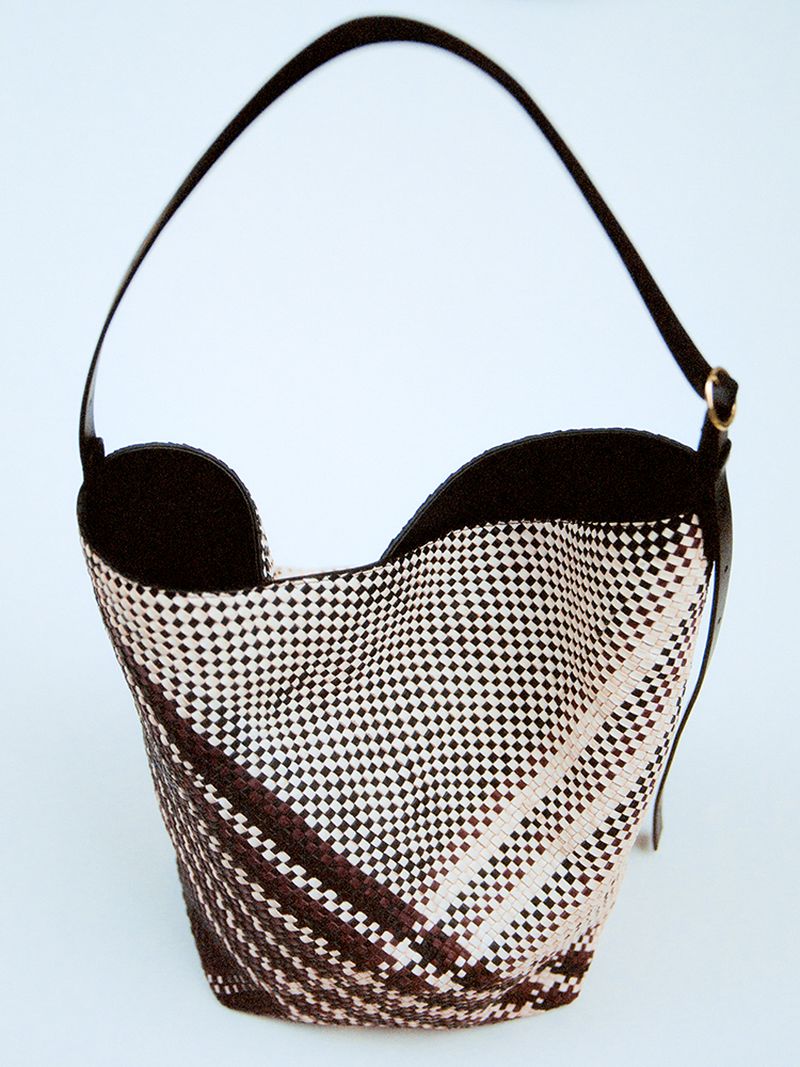 Woven tote bag with black leather trim and handle, presented against a neutral background, showcasing a geometric pattern.