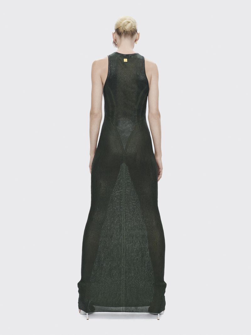 Back view of an adult female fashion model wearing a green, sleeveless, floor-length dress against a white backdrop in a studio.