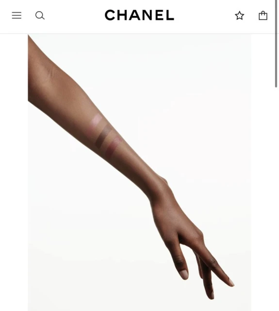 Close-up shot of a Black woman's arm with makeup swatches on fair background, showcasing beauty product tones and application.