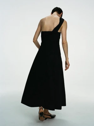 Model wearing a black one-shoulder dress seen from behind against a plain white studio background.