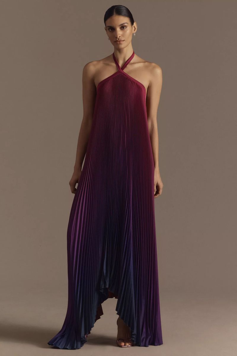 Fashion shoot of a woman in a halter maxi dress with pleated fabric. The dress features an ombre effect from burgundy to blue.