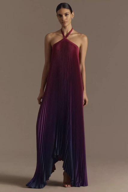 Fashion shoot of a woman in a halter maxi dress with pleated fabric. The dress features an ombre effect from burgundy to blue.