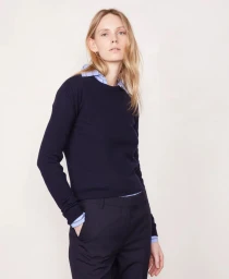 Model wearing a dark blue crewneck sweater over a light blue patterned shirt against a plain white background
