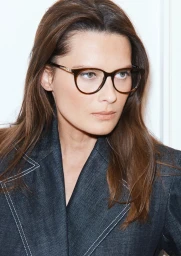 Close-up portrait of model Elena Melnik wearing dark round eyeglasses and a dark denim jacket for Guy Laroche Spring-Summer 24.