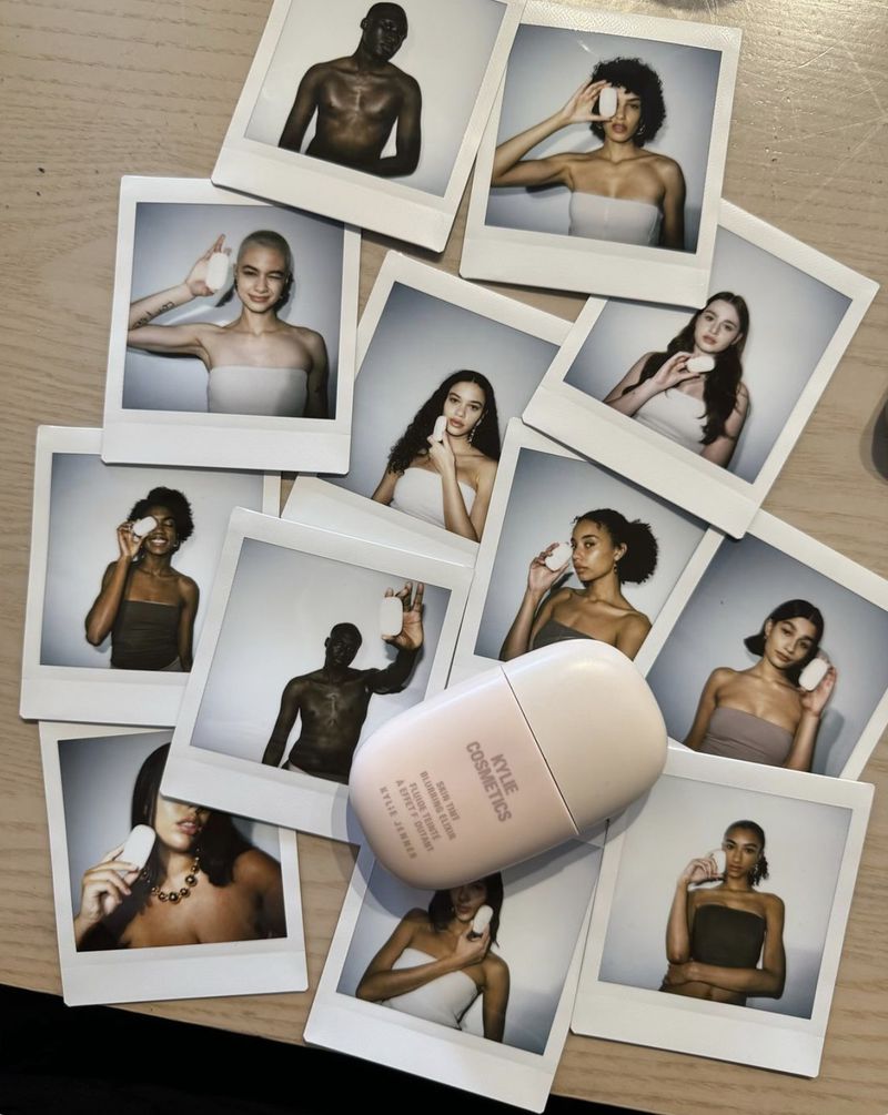 Cosmetics flat lay featuring Polaroid photos of diverse models applying a product, arranged around a pink and white Kylie Cosmetics container.