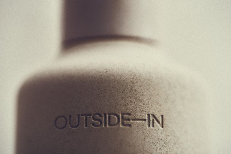 Close-up of a textured, light-grey container with the inscription 'OUTSIDE-IN', showcasing simplicity and a subtle message.