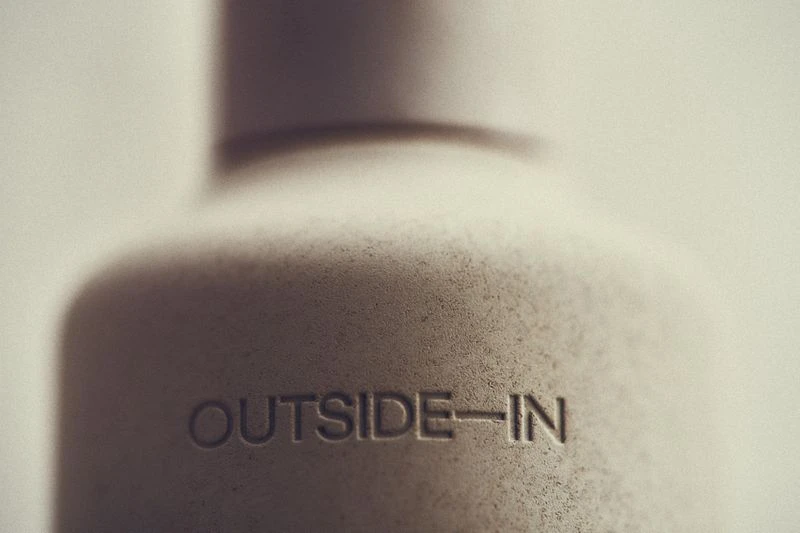 Close-up of a textured, light-grey container with the inscription 'OUTSIDE-IN', showcasing simplicity and a subtle message.