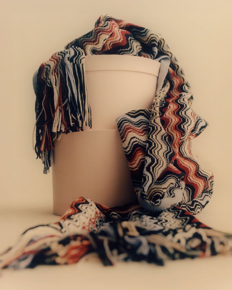 Zigzag pattern scarf draped over a light pink round box in a studio setting, creating a visually appealing fashion still life.