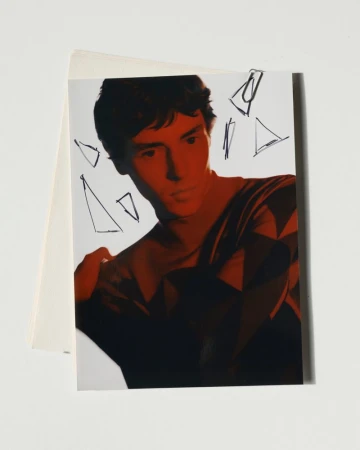 Artistic portrait of a dark-haired man with red color grading, posing in front of a white background, with geometric pencil drawings.