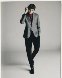 Model Valeriy Pakhomov wearing a grey tailored blazer, burgundy turtleneck, and black trousers against a neutral studio backdrop.