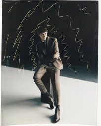 Valeriy Pakhomov seated in a tailored brown suit with graphic yellow line drawings against a dark studio background.