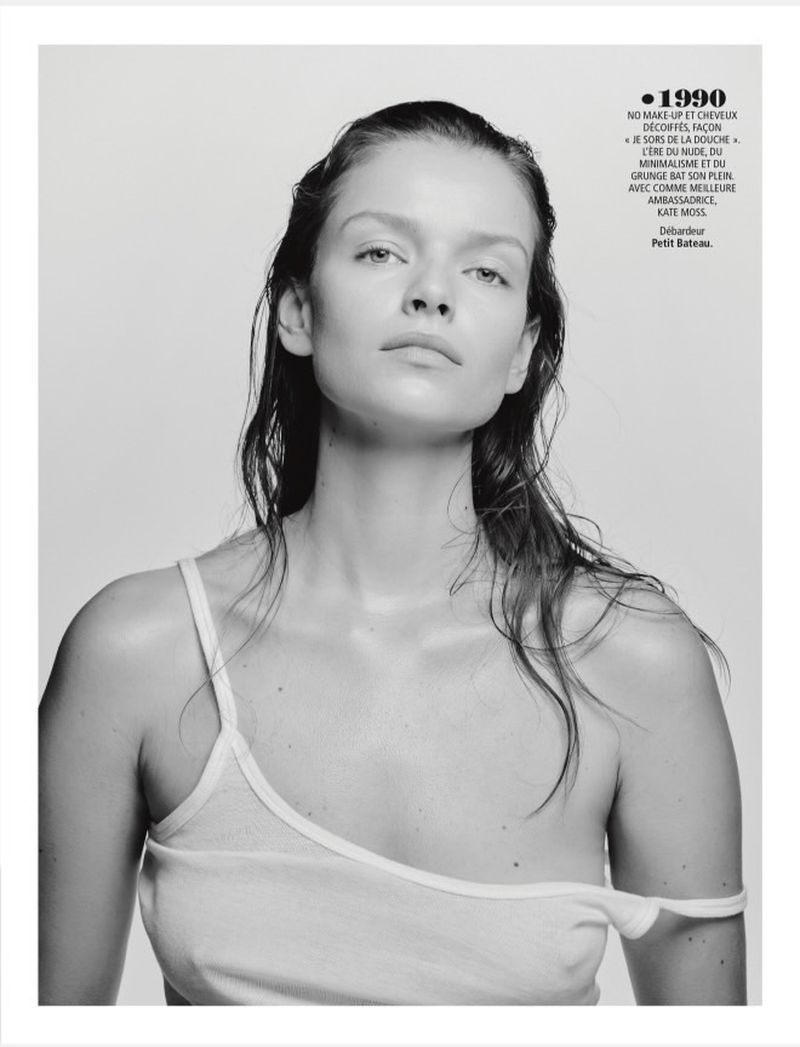 Black and white portrait of a young woman with wet hair wearing a white tank top against a light gray background.
