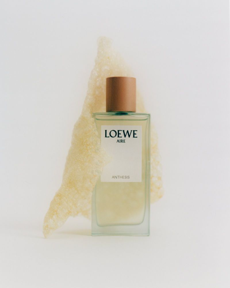 Loewe Aire Anthesis perfume bottle with textured material on a light background, close-up studio shot for beauty and fashion.