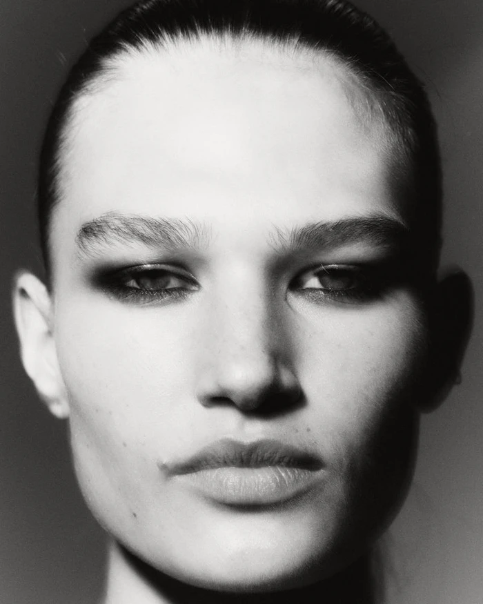 Black and white close-up portrait of model Emmi Freeman with smoky eye makeup looking directly at the camera.