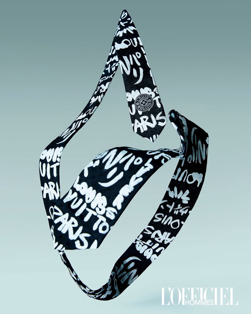 Black and white patterned necktie with 'Louis Vuitton Paris' text and logo floating in the center against a light blue background.