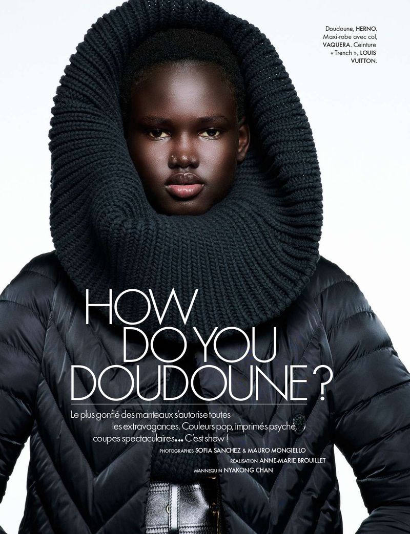 Fashion editorial featuring a dark-skinned female model wearing a black puffer jacket and oversized black knit cowl neck against a light background.