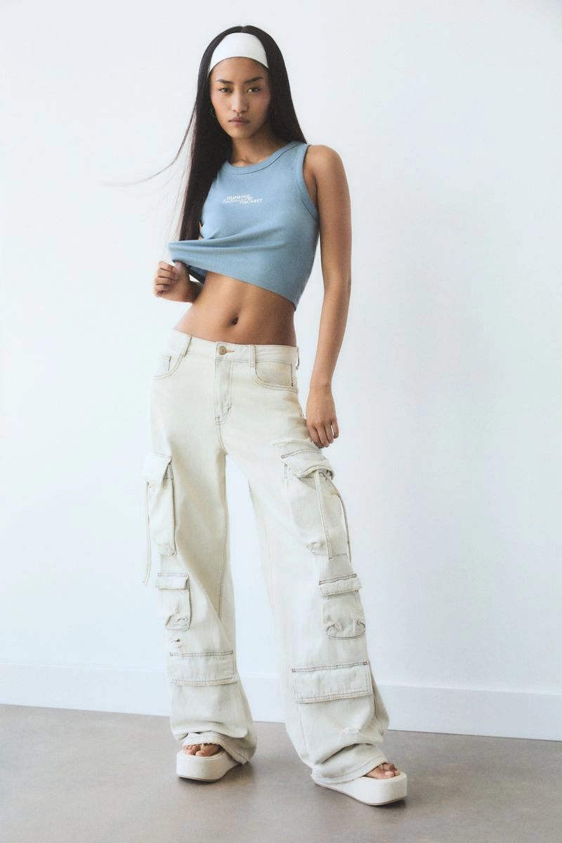 Model wearing blue crop top and light cargo pants against a white background for Pull and Bear