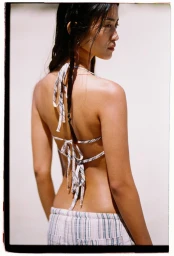 Model wearing a patterned halter top and striped shorts photographed against a white background.