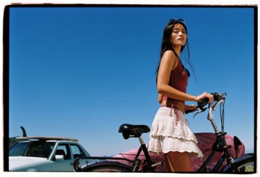 Model standing outdoors with a bicycle against a clear blue sky, photographed by Claudia Maturana for Pull & Bear Pacific Republic.