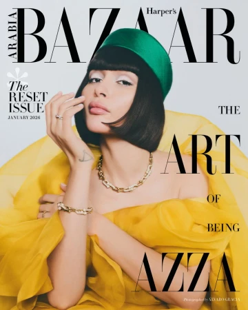 Magazine cover featuring woman with green hat and yellow dress, wearing gold jewelry with white background and black text logo.
