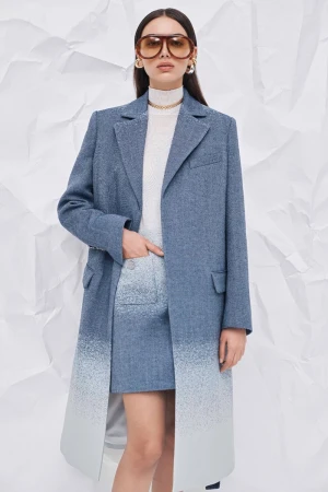 Woman in blue tweed coat and skirt with an ombre effect, accessorized with oversized sunglasses and gold jewelry against a white background.