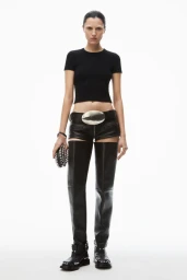 Model in black t-shirt and leather shorts with thigh-high boots against white background for Alexander Wang