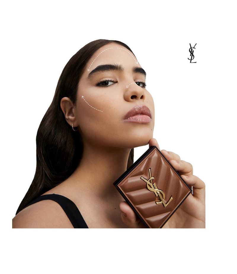 Cosmetic ad features a woman holding a YSL bronzer. The warm lighting highlights her makeup, hair, and beauty product.