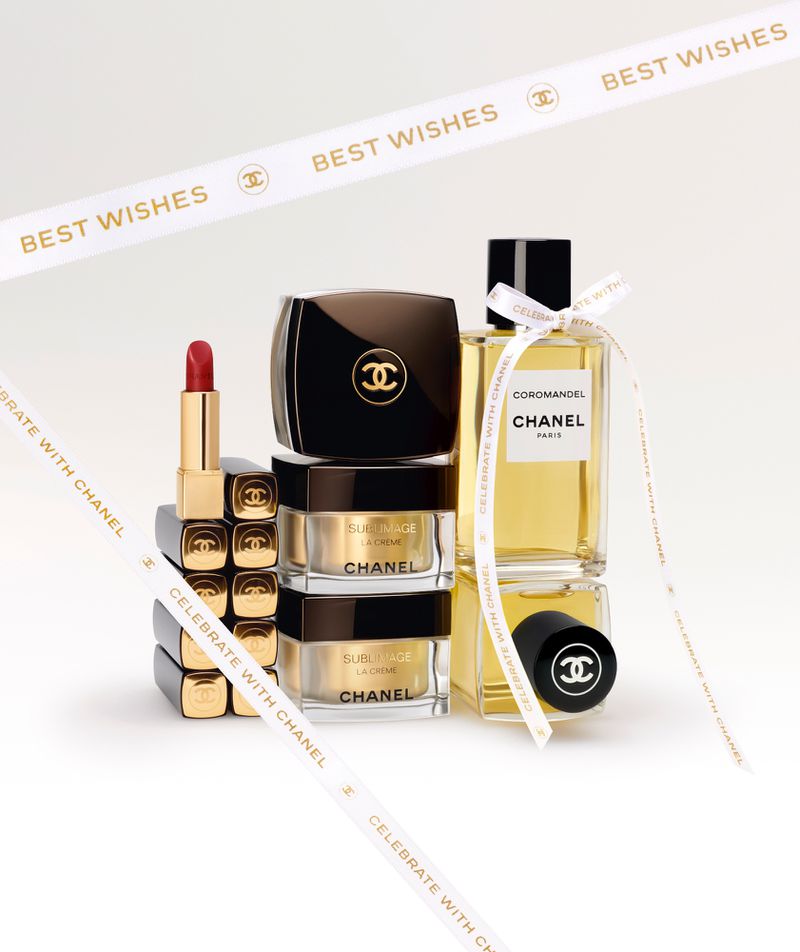 Beauty still life of Chanel skincare and fragrance products, including lipstick, cream, and perfume, arranged on a white background.