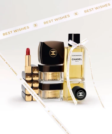 Beauty still life of Chanel skincare and fragrance products, including lipstick, cream, and perfume, arranged on a white background.