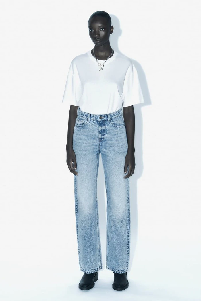 Model Assa Baradji wearing a white t-shirt and light wash jeans against a bright white background for Zara.