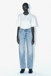 Model Assa Baradji wearing a white t-shirt and light wash jeans against a bright white background for Zara.