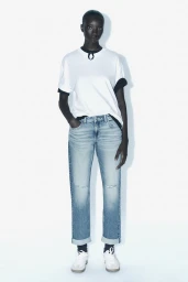 Model standing in light blue denim jeans and a white t-shirt against a plain white background for Zara.