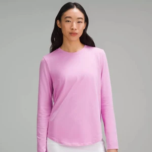 Model wearing a long-sleeve pink shirt against a plain grey seamless background for lululemon e-commerce.